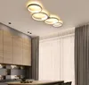 A modern kitchen with wooden cabinets, a sleek island, and a contemporary ring-shaped ceiling light. Produktbild-Vorschau