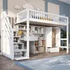 A white loft bed with integrated desk, shelves, and wardrobe, set in a child's bedroom with decorative clouds on the wall. Náhled obrázku produktu