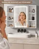 A woman is looking into a lighted mirror in a modern bathroom, with a sink and vanity visible. Voir les images du produit