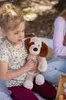 A young girl holding a stuffed dog outdoors. Produktbild-Vorschau