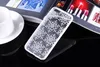 A white phone case with a mandala pattern is placed on a reflective black surface, next to a white cup and saucer. In the background, an open magazine displays images of clothing, lipstick, and a Coca-Cola bottle. Produktbild-Vorschau