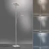 A modern LED floor lamp with a square top light and an adjustable reading light, shown against a gradient gray background. The image is composed of a main product shot and three smaller inset images showcasing the lamp under different lighting conditions. Produktbild-Vorschau