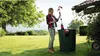 A woman is using a rain barrel pump in a garden. Produktbild-Vorschau