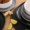 A close-up view of ceramic plates and bowls, with ginger and lime slices arranged on a wooden surface. Náhled obrázku produktu