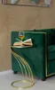 A close-up shot of a gold side table next to a green velvet sofa, with a book and a glass of wine on the table. Anteprima dell’immagine prodotto