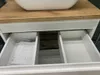Close-up view of an open bathroom vanity drawer showing a manual. Podgląd zdjęcia produktu