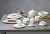 A collection of white ceramic tableware and drinkware is arranged on a gray surface. Anteprima dell’immagine prodotto