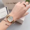 A person's wrist wearing an Emporio Armani watch and bracelet, with the product box in the background. Produktbild-Vorschau