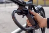 A hand is holding a bicycle lock attached to the handlebars of a bicycle. Produktbild-Vorschau