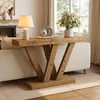 A wooden console table with a V-shaped base is placed behind a sofa in a living room, with a lamp and decorative items on top. Podgląd zdjęcia produktu