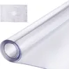 A roll of clear plastic tablecloth protector is shown diagonally across a white background. A small inset image shows a white rectangular placemat with a decorative pattern. Podgląd zdjęcia produktu