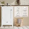 A white bathroom vanity cabinet with a drawer and a door, next to a woven laundry basket. The background shows a mirror and wallpaper. Produktbild-Vorschau
