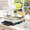 A dish drying rack filled with dishes and glasses, placed on a kitchen counter next to a sink. Podgląd zdjęcia produktu