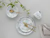 A flat lay of a dinnerware set with a sprig of greenery. Náhľad obrázku produktu