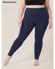 Plus-size-Model trägt dunkelblaue High-Waist-Leggings und einen schwarzen Sport-BH, steht barfuß