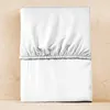A folded white fitted sheet is laid flat on a light brown wooden surface. Produktbild-Vorschau