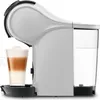 A side view of a white automatic capsule coffee machine with a glass of layered coffee in front of it and a water tank on the right. Produktbild-Vorschau