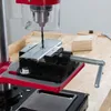 Close-up of a drill press with a metal piece being drilled, held by a vise. Produktbild-Vorschau