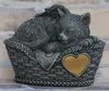 A sleeping cat figurine with wings, resting in a basket, with a heart-shaped plaque. Anteprima dell’immagine prodotto
