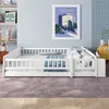 A white wooden children's bed with railings and bedding is shown in a room with a light blue wall and a purple rug. Produktbild-Vorschau