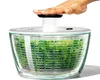 A hand pressing down on the lid of a salad spinner filled with green lettuce. Náhled obrázku produktu