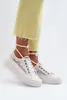 A person wearing yellow jeans and white lace sneakers with white laces tied around the ankles. Voir les images du produit