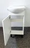 A white bathroom cabinet with a sink on top, and one door open, showing the interior. The cabinet is standing on black legs. Podgląd zdjęcia produktu