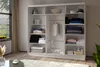 A white wardrobe with sliding doors is shown, filled with neatly folded clothes and accessories. Produktbild-Vorschau