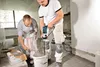 Two men are mixing material in a bucket with a power mixer. Anteprima dell’immagine prodotto