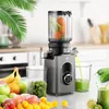 A slow juicer is shown in a kitchen setting, surrounded by fresh fruits and vegetables, with juice being dispensed into a glass. Produktbild-Vorschau