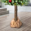 The base of a decorated artificial Christmas tree with a real trunk, set on a wooden floor. Podgląd zdjęcia produktu