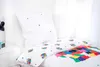 A bed with white bedding featuring a colorful geometric pattern and small square accents. Produktbild-Vorschau
