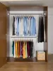 An open wardrobe with two hanging rods displaying various shirts and trousers, and a woven basket on the bottom shelf. Produktbild-Vorschau