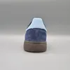 A rear view of a blue Adidas Handball Spezial sneaker against a plain gray background. Voir les images du produit