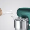 A hand is pouring liquid from a glass carafe into a stand mixer. Produktbild-Vorschau