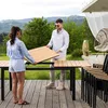 A couple is assembling an extendable garden table on a wooden deck with a scenic mountain view in the background. Produktbild-Vorschau