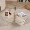 A round glass coffee table with a travertine base, decorated with a candle, a diffuser, and a vase with branches. A magazine is placed on the table. Anteprima dell’immagine prodotto