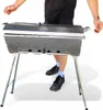 A person is standing behind a grill with its lid closed. Produktbild-Vorschau