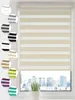 A close-up view of a cream and white striped roller blind covering a window with a city skyline visible in the background. Produktbild-Vorschau
