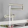 A wall-mounted kitchen faucet with water running into a sink. Podgląd zdjęcia produktu