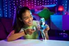 A young girl is playing with a doll in a bedroom decorated with string lights. Produktbild-Vorschau