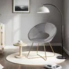 A modern living room scene with a gray velvet accent chair, a small side table with teacups, and a floor lamp. Produktbild-Vorschau