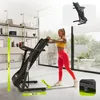 A woman is using a treadmill in a bright, modern room with large windows. Produktbild-Vorschau