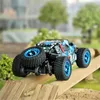 A remote-controlled off-road car is shown climbing over a wooden ramp in an outdoor setting. Produktbild-Vorschau