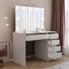 A white makeup vanity with a large illuminated mirror and multiple drawers, set in a room with curtains and a framed picture. Voir les images du produit