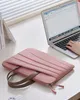 A pink laptop sleeve with handles is placed on a desk next to an open laptop. Produktbild-Vorschau