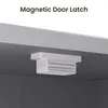 A close-up view of a magnetic door latch attached to the underside of a cabinet. Voir les images du produit