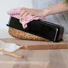 A person is removing a loaf of bread from a black loaf pan, which is placed on a wooden cutting board. Podgląd zdjęcia produktu