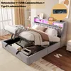 A bed with its storage compartment open, showing items inside, and illuminated by LED lights. Produktbild-Vorschau
