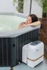 A woman relaxing in a hot tub next to its control unit. Produktbild-Vorschau